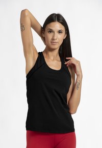 Zwarte tanktop met een ronde hals, gemaakt van zachte stof, gecombineerd met rode leggings. Bevat gestikte naden en heeft een relaxte pasvorm.