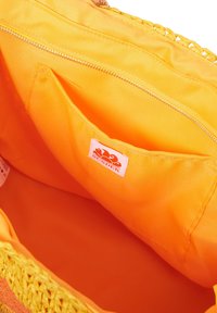 L'interno della borsa a tracolla gialla presenta una vivace fodera arancione, una tasca con zip e zip dorata, e un'etichetta con il logo. Texture liscia in tutto.