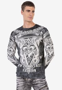 Schwarzes langärmliges T-Shirt mit aufwendigen weißen Grafikdesigns von einer Schlange und Fleur-de-Lis, Rundhalsausschnitt und einer weichen Textur.