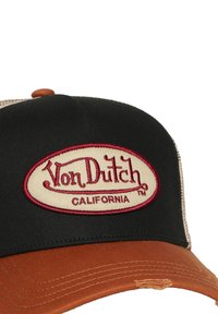 Casquette de baseball noire avec un patch ovale beige brodé en rouge indiquant "Von Dutch CALIFORNIA". Visière marron avec des détails brodés.