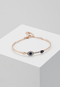 Rose gold bracelet featuring an eye motif with a navy stone center and clear accents, attached via a chain for adjustable length.