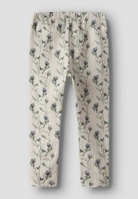 Leggings à motif floral avec une ceinture élastique. Fond beige clair avec des fleurs bleues et vertes sur un tissu texturé.