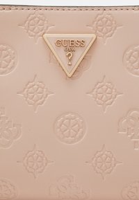 Portafoglio rosa chiaro con motivi floreali e geometrici in rilievo, dotato di una placca decorativa a forma di triangolo dorata sul davanti. Texture liscia.
