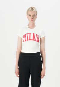 Hvit bomulls t-skjorte med rødt "MILAN"-design, korte ermer og en cropped stil, sammen med svarte relaxed fit bukser.
