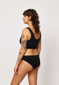 Zwart ondergoedset bestaande uit een aansluitende crop top met brede banden en een middelhoge broekje, gemaakt van zacht materiaal. Glad textuur zonder patronen.