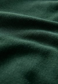 Getextureerde donkergroene stof met een subtiel geribd patroon, met een glad oppervlak en zachte uitstraling.