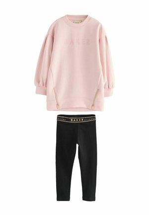 Helles rosa Pullover mit BAKER-Logo und seitlichen Reißverschlusstaschen, kombiniert mit schwarzen Leggings mit goldenem Akzent an der Taille.