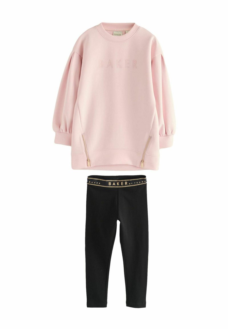 Lichtroze pullover met BAKER-logo en zijzakken met rits, gecombineerd met zwarte leggings met een goudaccent in de tailleband.