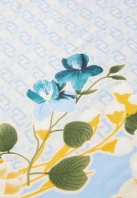 Tessuto floreale con fiori blu e turchesi su uno sfondo azzurro a motivo; presenta foglie verdi e accenti gialli.