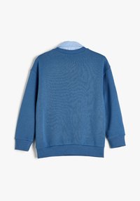 Sudadera azul con un acabado texturizado, puños y dobladillo acanalados. Presenta un collar de color azul claro y un corte holgado y relajado.