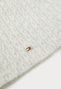 Kootud helesinine kangas, millel on tekstureeritud rombimuster; esindab väikest kuldset embleemi punaste ja siniste aktsentidega.