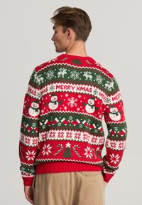 Maglione di Natale lavorato a maglia con un motivo rosso, verde e bianco che presenta pupazzi di neve, renne e fiocchi di neve. Polsini e orlo a coste.