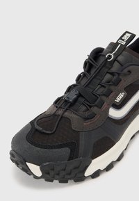 Black and gray sneaker featuring mesh, suede, and rubber materials, with a textured sole, elastic laces, and a white Vans logo.