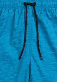Niebieskie spodenki kąpielowe z teksturowanej tkaniny i czarnym sznurkiem w pasie, zaprojektowane z elastycznym pasem dla pewnego dopasowania.