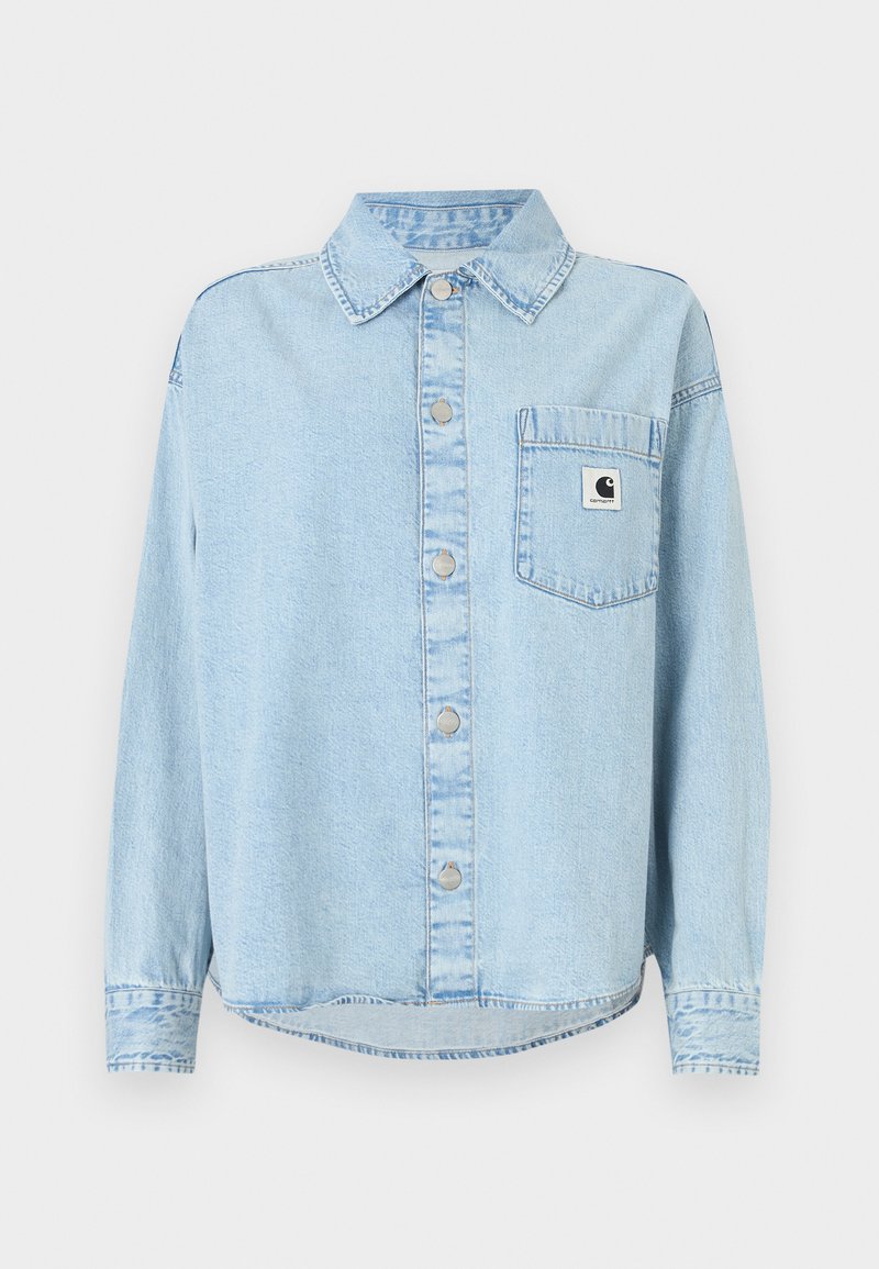Light blue denim shirt with a front pocket, button-down closure, and long sleeves. Features a logo patch on the pocket and visible stitching.