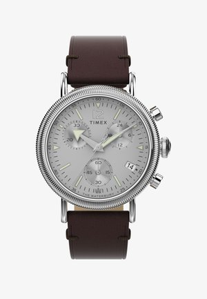 Timex waterbury watch featuring a silver dial with three sub-dials, silver-tone hardware, and a brown leather strap. Rotating bezel detail.