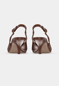 Escarpins slingback en cuir marron avec un design courbé, dotés d'une fine bride à la cheville et d'un talon aiguille de taille moyenne. Texture lisse.
