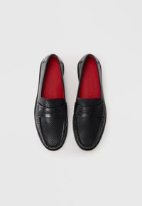 Sorte læder loafers med en tekstureret overflade og rød sål. Har et dekorativt bånd over forsiden med syninger.