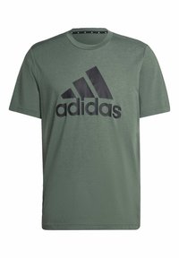 Olivgrön bomulls t-shirt med en svart Adidas-logotyp på framsidan, kort ärm och rundad halsringning. Enkel och vanlig passform.