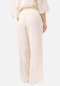 Leichte, cremefarbene, strukturierte weit geschnittene Hosen mit elastischem Bund und weichem, atmungsaktivem Stoff.