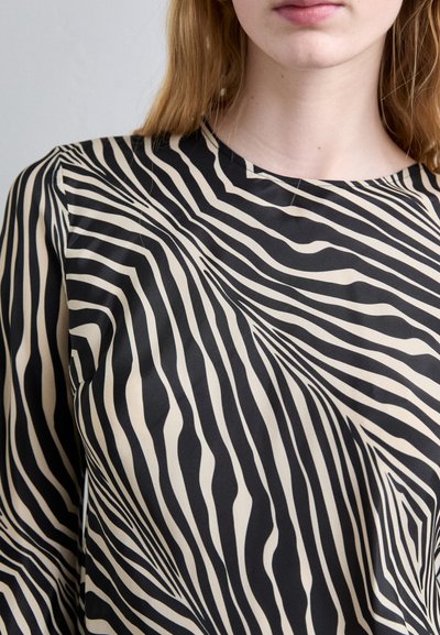 Black and beige long-sleeve top with a wavy zebra stripe pattern, featuring a subtle neckline and smooth fabric texture.