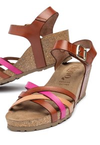 Bruine leren wedge sandalen met roze, beige en bruine banden. Kurk bedekte zool, verstelbare enkelband met een gesp, en een gestructureerde zool.