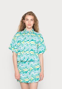 Camisa de manga curta e saia combinando com um padrão ondulado em verde, azul e branco. Feita de um tecido suave com um corte descontraído.