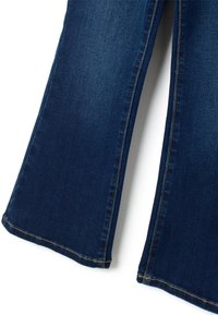 Jeans acampanados de denim azul oscuro con una textura suave, que presentan costuras en amarillo contrastante a lo largo de las costuras y un ligero dobladillo deshilachado.