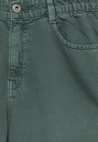 Pantalon vert à texture douce, avec une ceinture élastique, une fermeture avant à boutons et des poches latérales.