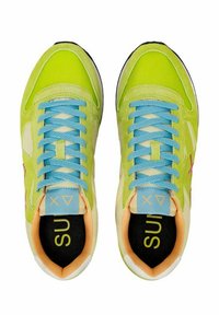Sneaker verde lime con lacci blu, dettagli crema e una soletta nera con la scritta "SUI" in giallo. Materiali in suede e rete utilizzati.