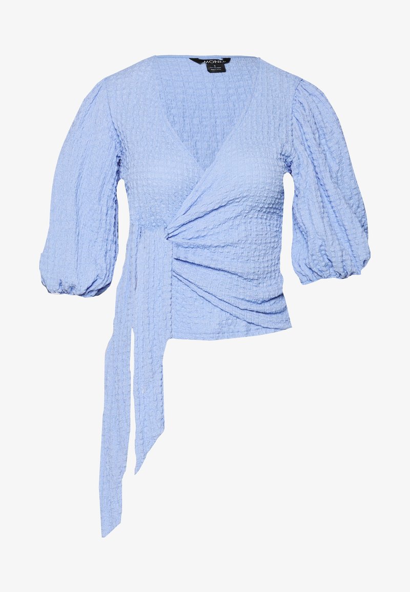 Light blue wrap top made of textured fabric. Features deep V-neck, puff sleeves, and a side tie detail for adjustable fit.