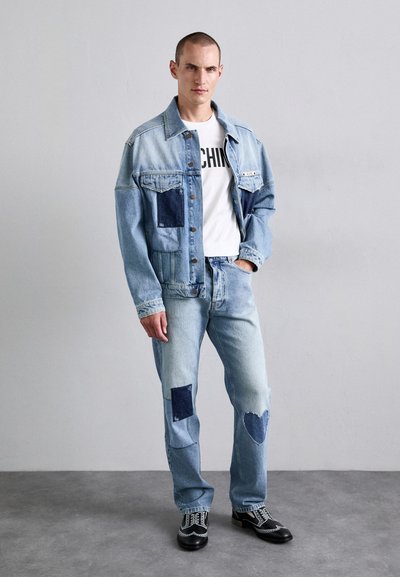 Blå denimjacka med lappar, i kombination med matchande ljusblå jeans som har hjärt- och fyrkantiga lappar. Vit t-shirt med svart text under.
