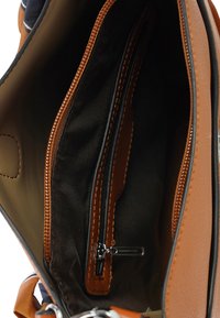 Binnenkant van een bruin leren tas met meerdere vakken, waaronder een ritsvak met zwarte stofvoering en oranje stiksels.