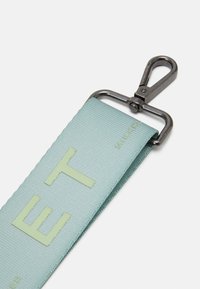 Svetle modrý textilní pásek s embosovanými písmeny, vybavený kovovou sponou na připojení. Textura je hladká s jemným leskem.