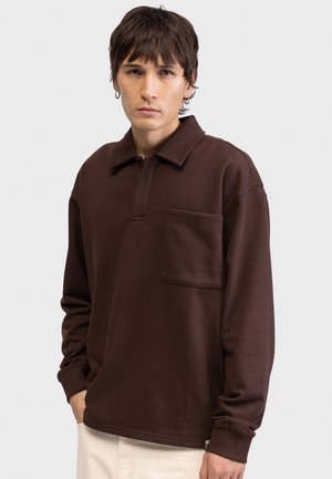 Barna hosszú ujjú galléros pólóvastag anyagból, gallérral, mellzsebbel és bordázott mandzsettákkal. Sima textúra, laza szabás.