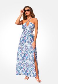 Maxi sukienka w kwiatowy wzór w odcieniach niebieskiego i fioletowego na białym tle. Posiada dekolt w kształcie łezki i boczne rozcięcie, wykonana z lekkiego materiału.