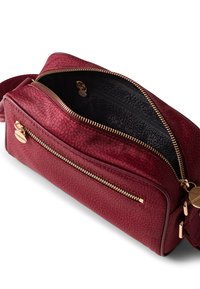 Red textured bag with a smooth finish, golden zippers, and a patterned black interior. Features a front pocket and adjustable strap.