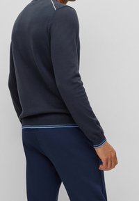 Suéter de color azul marino con puños y dobladillo acanalados, con una franja de acento en azul claro, combinado con pantalones joggers a juego en azul marino, de material de algodón.
