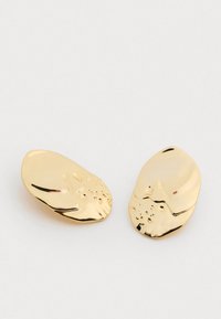 Náušnice z kovu v zlatom odtieni s hladkým, organickým tvarom, na jednej strane s jemným textúrovaným detailom. Veľmi lesklý povrch.