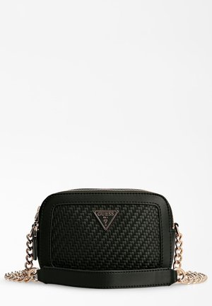 Sac bandoulière noir Guess avec texture tissée, bandoulière chaîne dorée et logo métallique triangulaire à l'avant sur fond blanc.