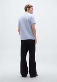 Γαλάζιο κοντομάνικο μπλουζάκι σε συνδυασμό με μαύρο τζιν φαρδιάς γραμμής, με λεία υφή και απλό σχέδιο.