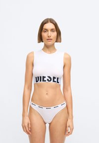Λευκό κοντό μπλουζάκι με μαύρη ζώνη "DIESEL", συνδυασμένο με λευκά μπικίνι που διαθέτουν ταιριαστό μαύρο λογότυπο στη ζώνη. Απαλή, εφαρμοστή ύφανση.
