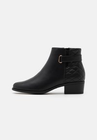 Bottines noires avec une tige en cuir lisse, motif matelassé à l'arrière et une boucle en métal doré ; petit talon carré.