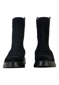 Bottines en suède noir avec une texture lisse, dotées de tirettes et d'une semelle en caoutchouc noir chunky, conçues pour un enfilage facile.