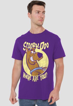 Man wearing purple T-shirt with large Scooby-Doo cartoon face and text "Scooby-Doo Where Are You?"