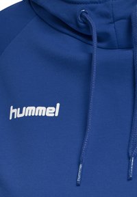 Felpa blu realizzata in tessuto liscio, con tasca frontale, cappuccio regolabile con cordini e logo "hummel" bianco sul petto.