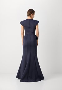 Robe ajustée bleu marine, avec de courtes manches à capuchon, fermeture éclair au dos et ourlet évasé. Présente des coutures structurées et une ceinture à la taille amovible.