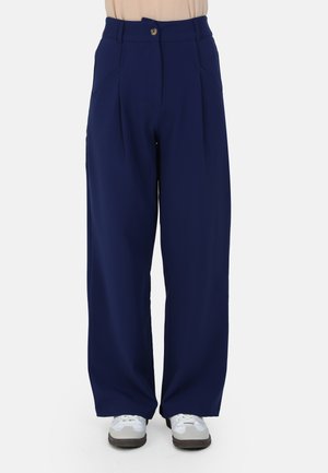 Navy wide-leg pants with pleats, button closure, and two side pockets; made from smooth, lightweight fabric. Paired with gray shoes.