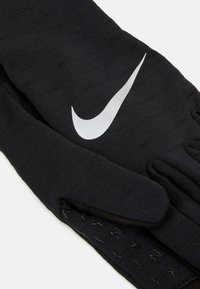 Gants en tricot noirs arborant le logo argenté de Nike, avec une texture lisse et une conception ajustée. Comprend des détails côtelés.