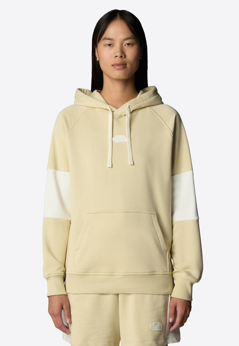 Felpa color crema con tasca a marsupio, maniche raglan e un accento bianco sulla manica. Presenta un piccolo logo sul petto.